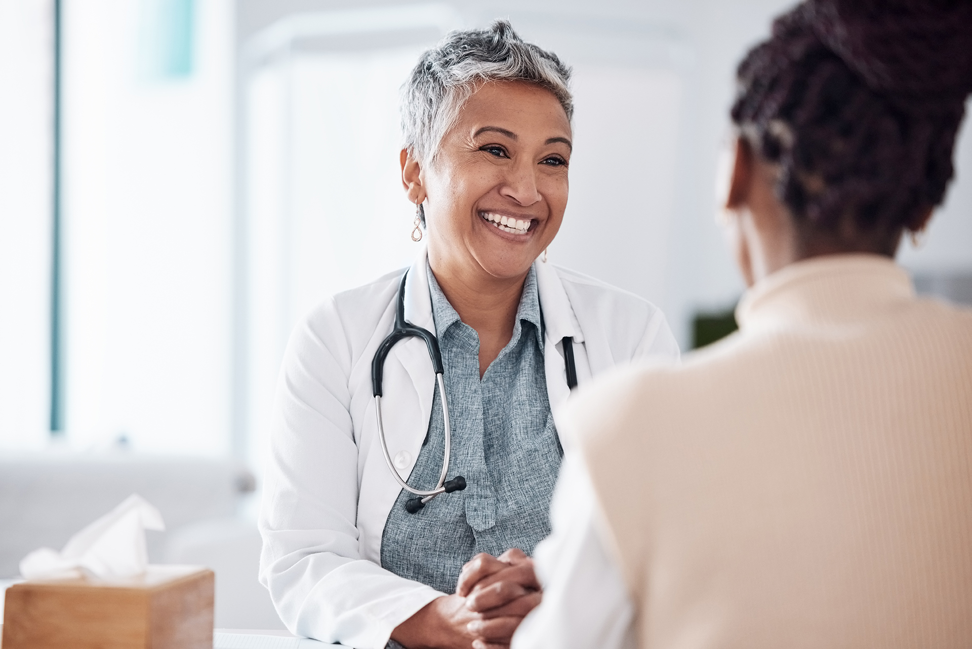 Happy, mature or doctor consulting a patient in meeting in hospital for healthcare help, feedback or support. People, medical or nurse with black woman talking or speaking of test results or advice.